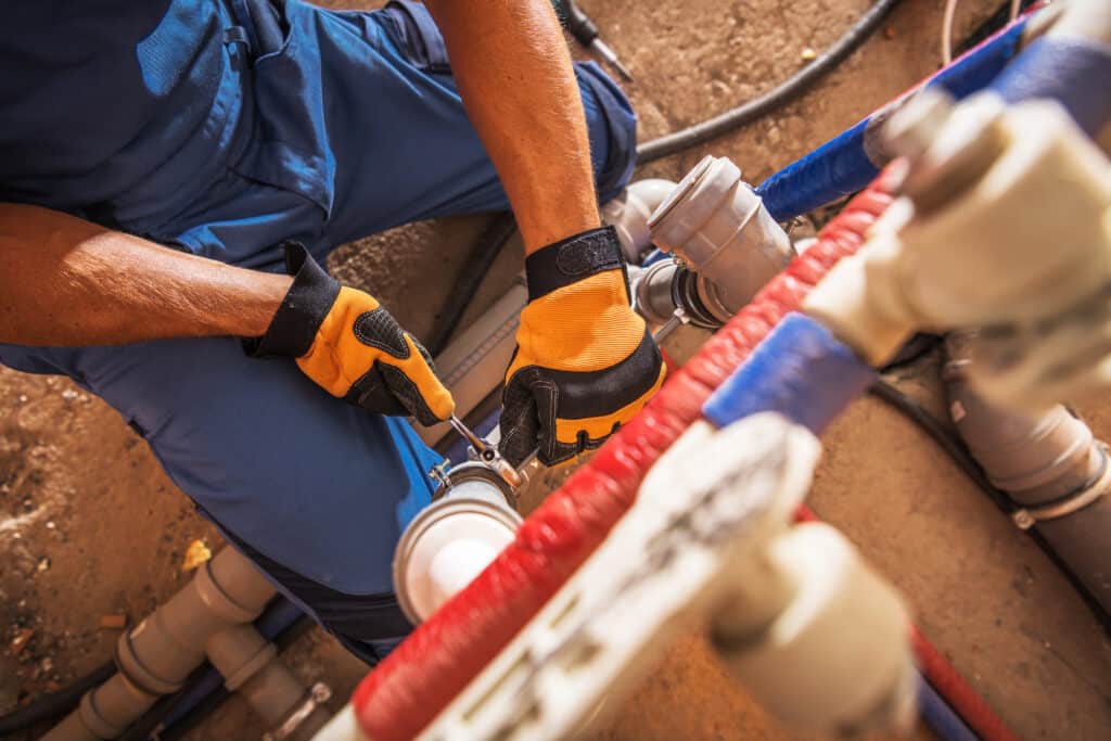 plumber working on pipes as a homeowner wonders what a slab leak sounds like