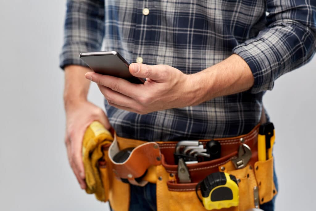 medium shot of plumber holding phone looking at ai chat bot responses in houston tx