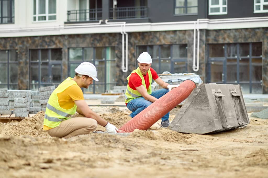 two men working on cast iron pipe wondering if trenchless sewer repair would work