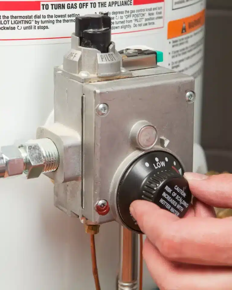 Technician adjusting the gas control valve on a water heater