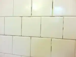 Cracked grout lines between white shower tiles
