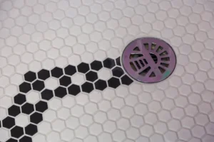 Mosaic tile shower pan sloping to a round drain
