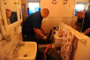 Two plumbers working in a small bathroom