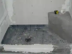 Black shower pan liner clamped to the drain before the mortar bed
