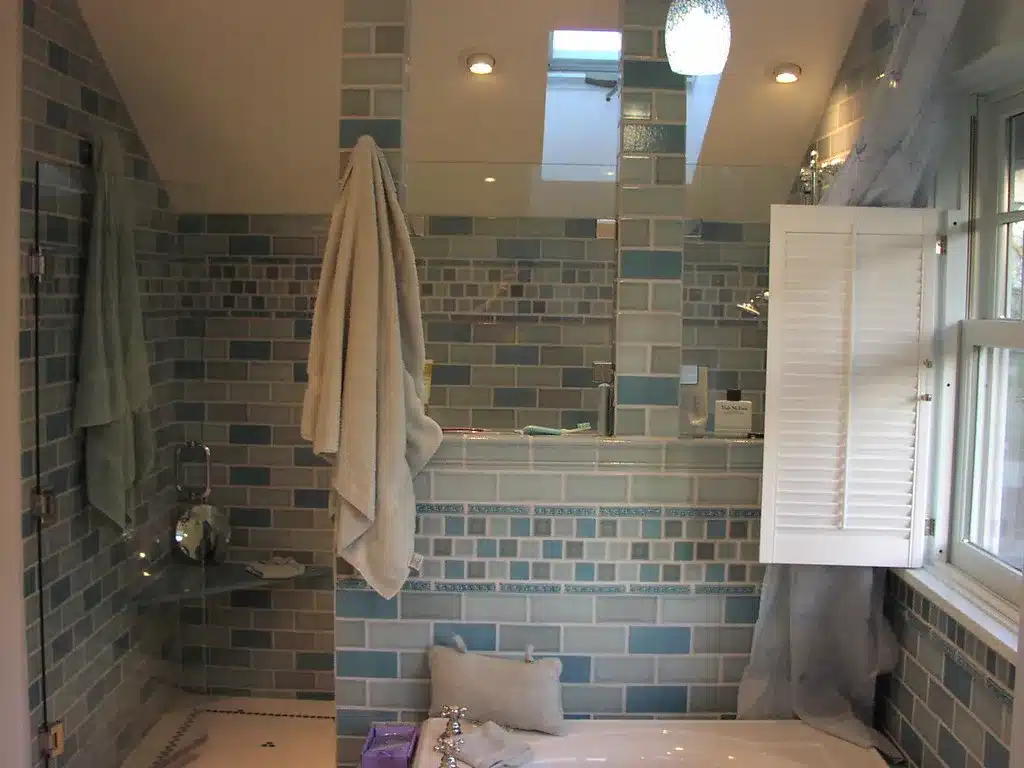 Tiled walk-in shower with a glass panel