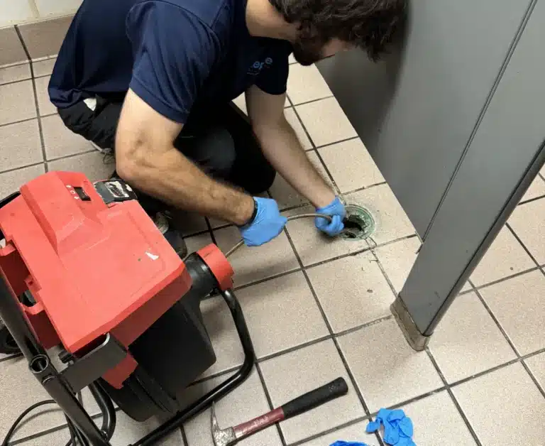 Plumber clearing a floor drain with a drain machine